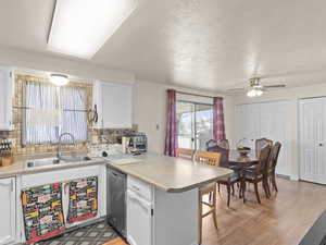 Kitchen featuring a peninsula, a breakfast bar, white cabinetry, backsplash, and a textured ceiling