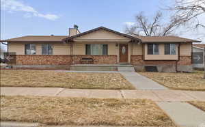 Ranch-style house featuring brick siding, a chimney, and a front lawn