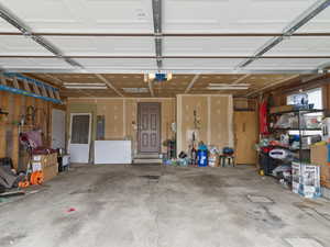Garage with white fridge, electric panel, and a garage door opener