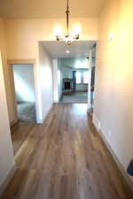 Corridor with dark wood-type flooring and a chandelier