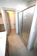 Full bathroom featuring a stall shower, vanity, and light tile patterned floors