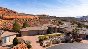 View of front of property with driveway, a mountain view, a garage, stone siding, and a tiled roof