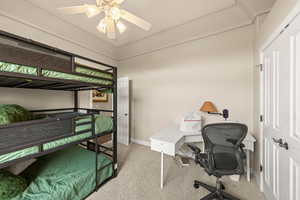 Bedroom featuring light carpet, an office area, and a ceiling fan