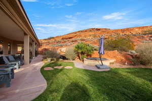 View of grassy yard featuring a patio and a mountain view