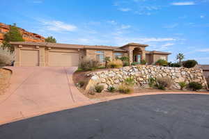 View of front facade with stucco siding, an attached garage, driveway, and stone siding