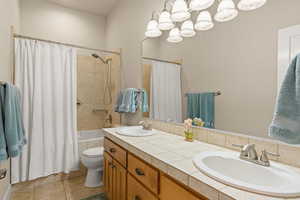 Bathroom featuring shower / tub combo, double vanity, and light tile patterned floors