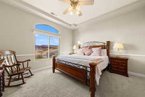 Bedroom featuring ceiling fan, a tray ceiling, light carpet, and a mountain view