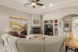 Living room featuring built in shelves, a tile fireplace, a ceiling fan, light carpet, and recessed lighting