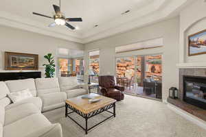 Carpeted living room featuring a raised ceiling, a tiled fireplace, plenty of natural light, ceiling fan, and recessed lighting