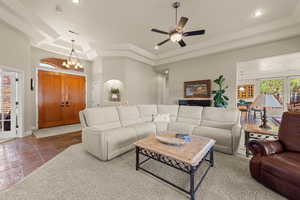 Living room featuring a tray ceiling, a chandelier, and a ceiling fan