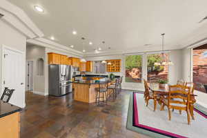Kitchen with stone finish floors, stainless steel appliances, a breakfast bar area, a kitchen island, and pendant lighting