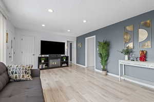 Living area with wood finished floors, a glass covered fireplace, a textured ceiling, and recessed lighting
