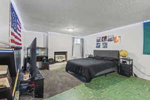 Bedroom featuring a fireplace and a textured ceiling
