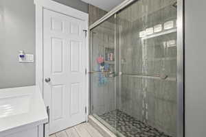 Full bathroom featuring vanity, a stall shower, and light wood-type flooring