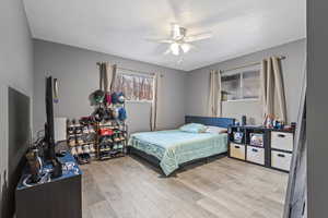 Bedroom featuring light wood-style flooring, a ceiling fan, and a textured ceiling