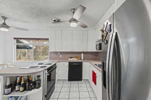Kitchen featuring appliances with stainless steel finishes, light countertops, white cabinetry, a textured ceiling, and light tile patterned flooring
