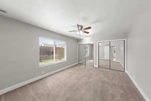 Unfurnished bedroom with multiple closets, carpet, ceiling fan, and a textured ceiling