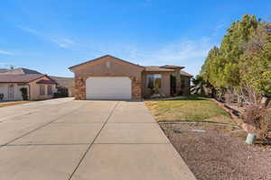 View of front of house featuring stone siding, driveway, a front yard, a garage, and stucco siding