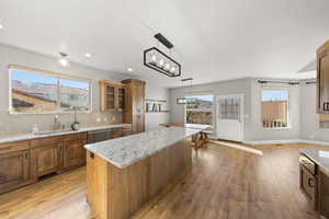 Kitchen featuring light wood-type flooring, brown cabinetry, and light stone counters