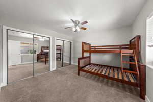 Carpeted bedroom with two closets and a ceiling fan