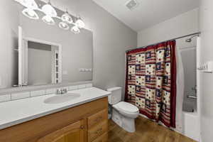 Bathroom featuring shower / tub combo, vanity, and dark wood-style floors