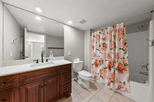 Full bathroom featuring shower / bathtub combination with curtain, vanity, light tile patterned flooring, and recessed lighting