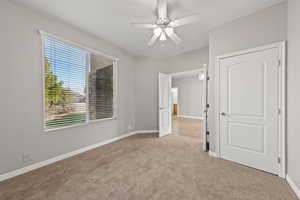 Unfurnished bedroom featuring light carpet and a ceiling fan