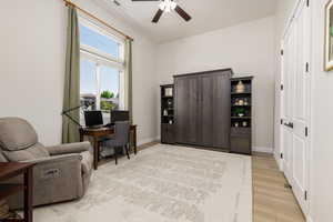Living area with a desk, a ceiling fan, and light wood-type flooring