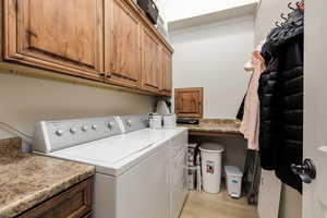 Laundry room featuring washer and clothes dryer, light wood-type flooring, and cabinet space