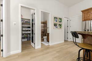 Kitchen featuring a kitchen breakfast bar, light wood finished floors, stainless steel fridge with ice dispenser, and wood finish cabinetry