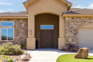 View of exterior entry with stone siding, a tile roof, and stucco siding