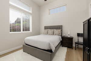 Bedroom with light wood-type flooring, multiple windows, and a ceiling fan