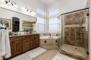 Bathroom featuring double vanity, a garden tub, a shower stall, light wood-style flooring, and a walk in closet