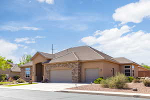 View of front of house with a tile roof, stucco siding, stone siding, and driveway