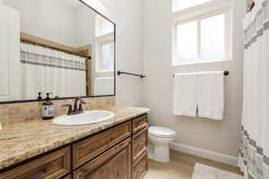 Bathroom featuring curtained shower, vanity, decorative backsplash, and light wood finished floors