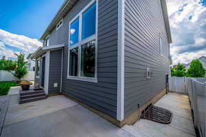 View of side of home featuring a fenced backyard, a patio, and a gate