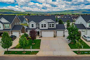 View of front facade with concrete driveway, stone siding, a residential view, and a mountain view