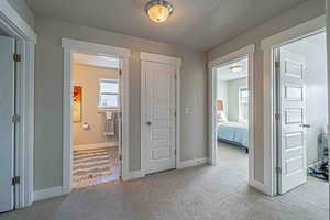 Hallway featuring a textured ceiling and light colored carpet