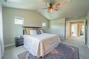 Bedroom featuring a textured ceiling, multiple windows, a ceiling fan, vaulted ceiling, and light carpet