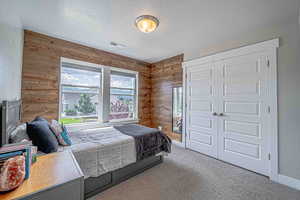 Bedroom with wood walls, carpet floors, and a textured ceiling