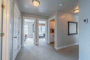 Hall featuring light colored carpet and a textured ceiling