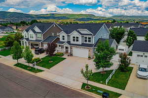 View of front of house with a mountain view, stone siding, a residential view, and concrete driveway