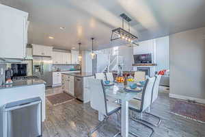 Dining space with stairs, dark wood-style floors, a textured ceiling, a fireplace, and recessed lighting