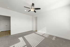 Carpeted spare room with baseboards and ceiling fan