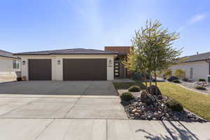 View of front of home featuring concrete driveway, an attached garage, stucco siding, and a front lawn