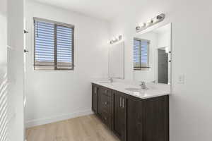 Full bath with double vanity and light wood finished floors