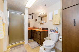 Bathroom with a stall shower, vanity, light floors, and a textured ceiling