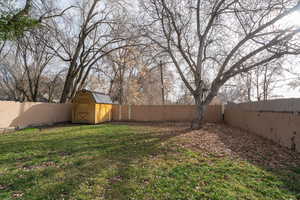 Fenced backyard featuring a storage shed