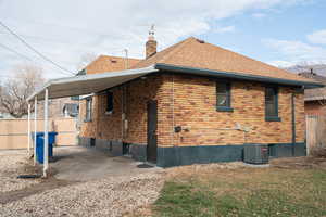 View of side of home featuring brick siding, a chimney, and a shingled roof