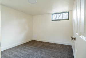 Spare room with dark colored carpet and baseboards